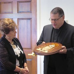 Stickley CEO Aminy Audi presents Bishop-elect Douglas J. Lucia with the coat of arms that will grace his cathedra come August 8. (Sun photo | Chuck Wainwright)